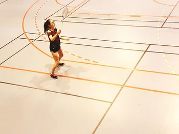 Full length of teenage girl playing with racket on sports court