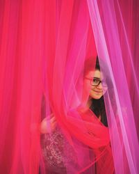 Portrait of woman standing by curtains