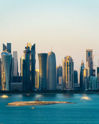 Modern buildings by sea against clear sky