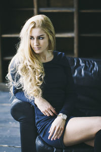 Beautiful young woman sitting on sofa at home