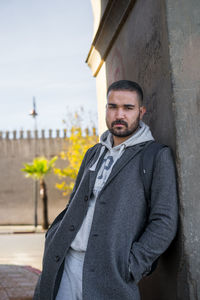 Moroccan man leaning against a wall wearing stylish grey coat