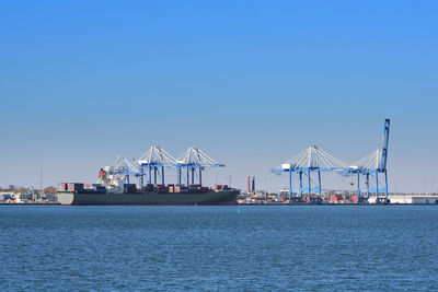 Cranes at commercial dock against clear blue sky