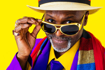 Man wearing sunglasses against yellow background