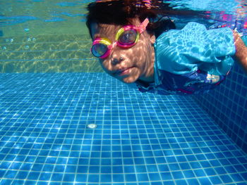 Girl wearing goggles swimming in pool