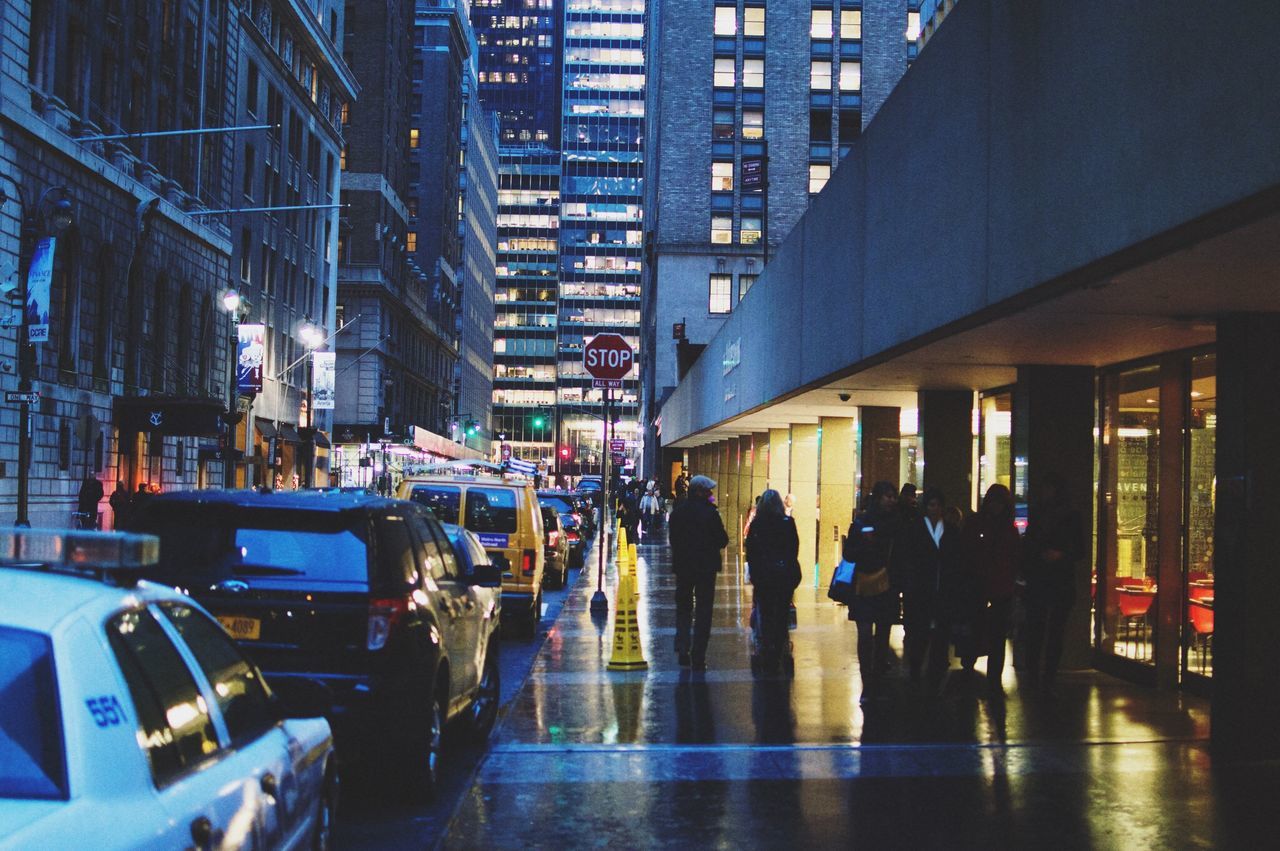 building exterior, architecture, city, built structure, transportation, city life, large group of people, street, mode of transport, men, person, car, land vehicle, walking, city street, building, lifestyles, reflection, traffic