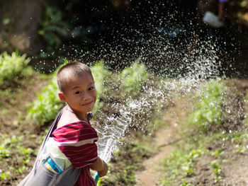 Portrait of girl watering garden with hose