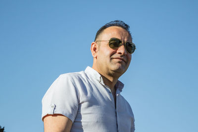 Low angle portrait of man against clear blue sky