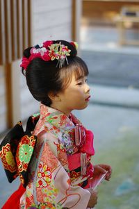 Cute girl in traditional clothing looking away while standing outdoors