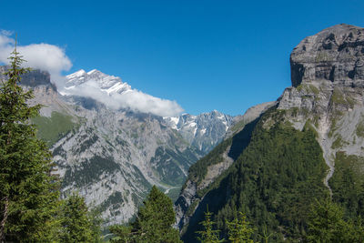 Low angle view of snowcapped mountains against blue sky