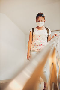 Woman wearing mask walking on staircase