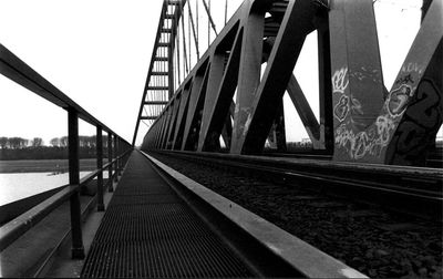 Bridge over railroad tracks in city against clear sky