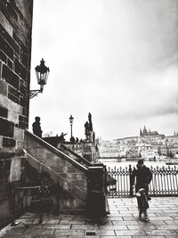 People on bridge against buildings in city