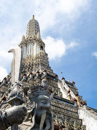 A statue of a guard at the wat arun temple, temple of dawn, in bangkok, thailand, against blue sky.
