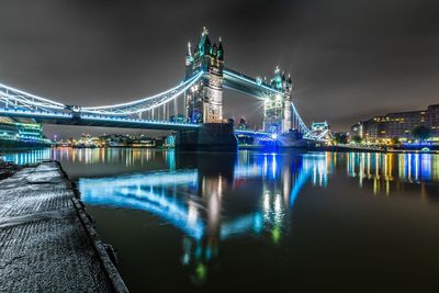 Illuminated tower bridge over thames river in city at night