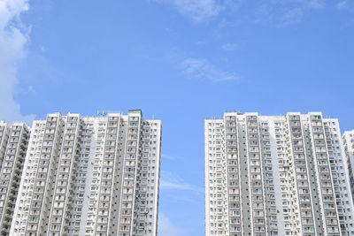 Low angle view of white apartment buildings against blue sky