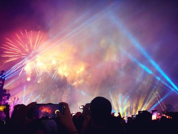 Group of people photographing firework display at night