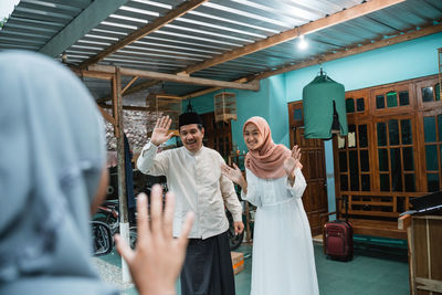 Man and woman waving guest at home