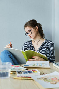 Millennial girl draws fabulous images on paper while sitting at home