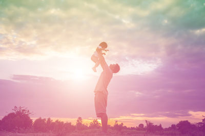 Man holding purple standing against sky during sunset