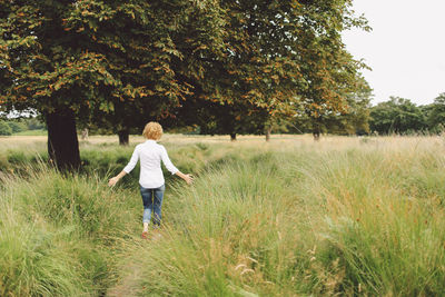 Rear view of young woman walking on grassy field