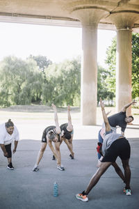 Male and female friends doing warm up exercises with instructor during training session