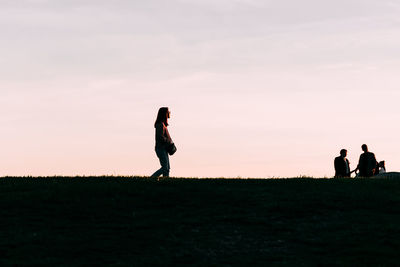 Woman walking on land against sky during sunset