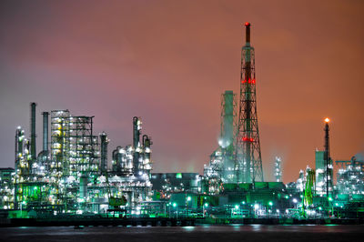 Illuminated factory against sky at night