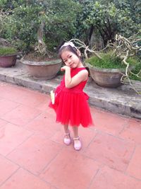 Full length of smiling girl standing against red wall