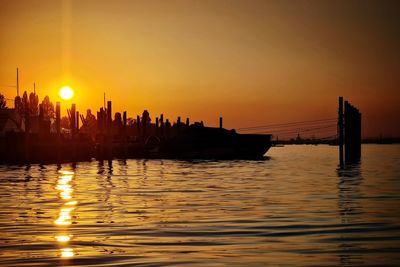 Silhouette boats in sea against orange sky