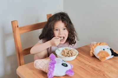 A girl is eating oatmeal breakfast at the kitchen table