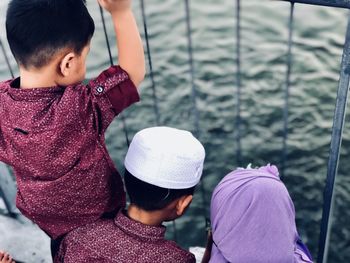 High angle view of children looking at sea through fence