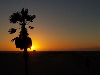 Silhouette trees on landscape against clear sky at sunset