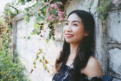 Portrait of beautiful woman standing by potted plant