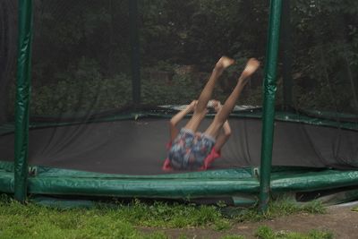 Boy jumping on trampoline against trees