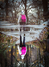 Rear view of woman with pink umbrella against trees in forest