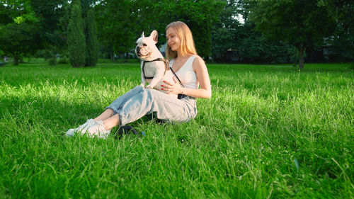 Woman with dog sitting on field