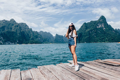 Portrait of woman standing on pier over lake 