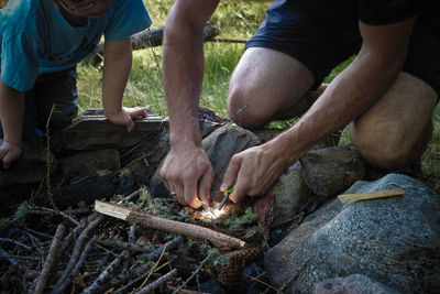 Cropped image of father and boy burning firewood