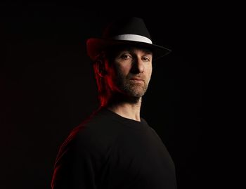 Portrait of man wearing hat against black background
