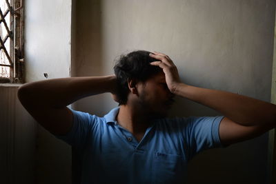 Portrait of man standing against wall at home. the man seems to be in depression.