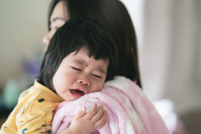Close-up of cute girl crying with mother