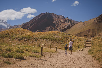 Rear view of men walking on mountain against sky