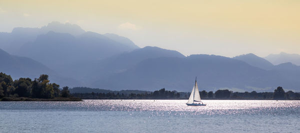 Sailboat sailing on sea against mountains