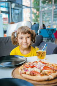 Cute girl sitting at table in restaurant