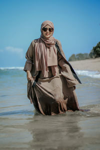 Low angle view of woman standing in sea against sky