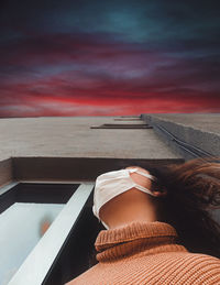 Rear view of woman sitting on swimming pool at sunset