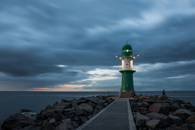 Lighthouse by sea against sky