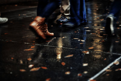 Low section view of three people on wet road