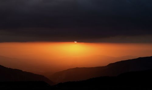 Scenic view of silhouette mountains against romantic sky at sunset