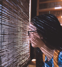 Side view of girl looking through window